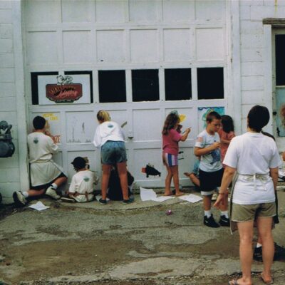 Historical photo of kids painting a garage door at a mural event
