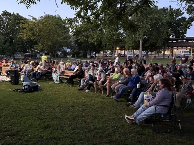 Group of people seated at a park waiting for event