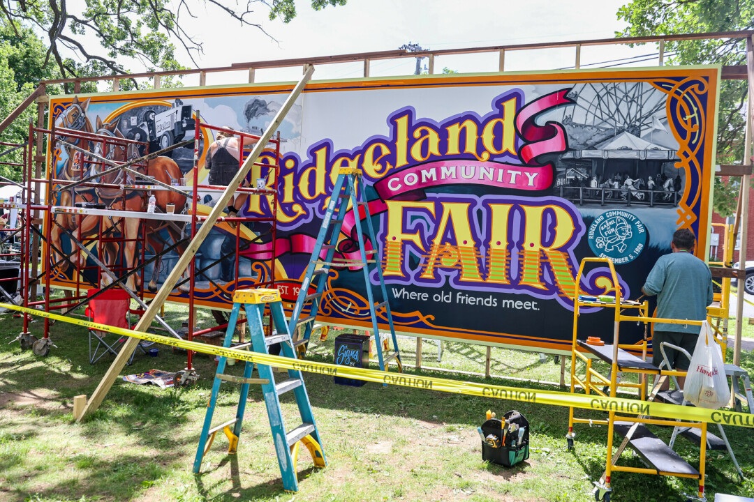 Large Billboard mural getting painted with scaffolding in front of it