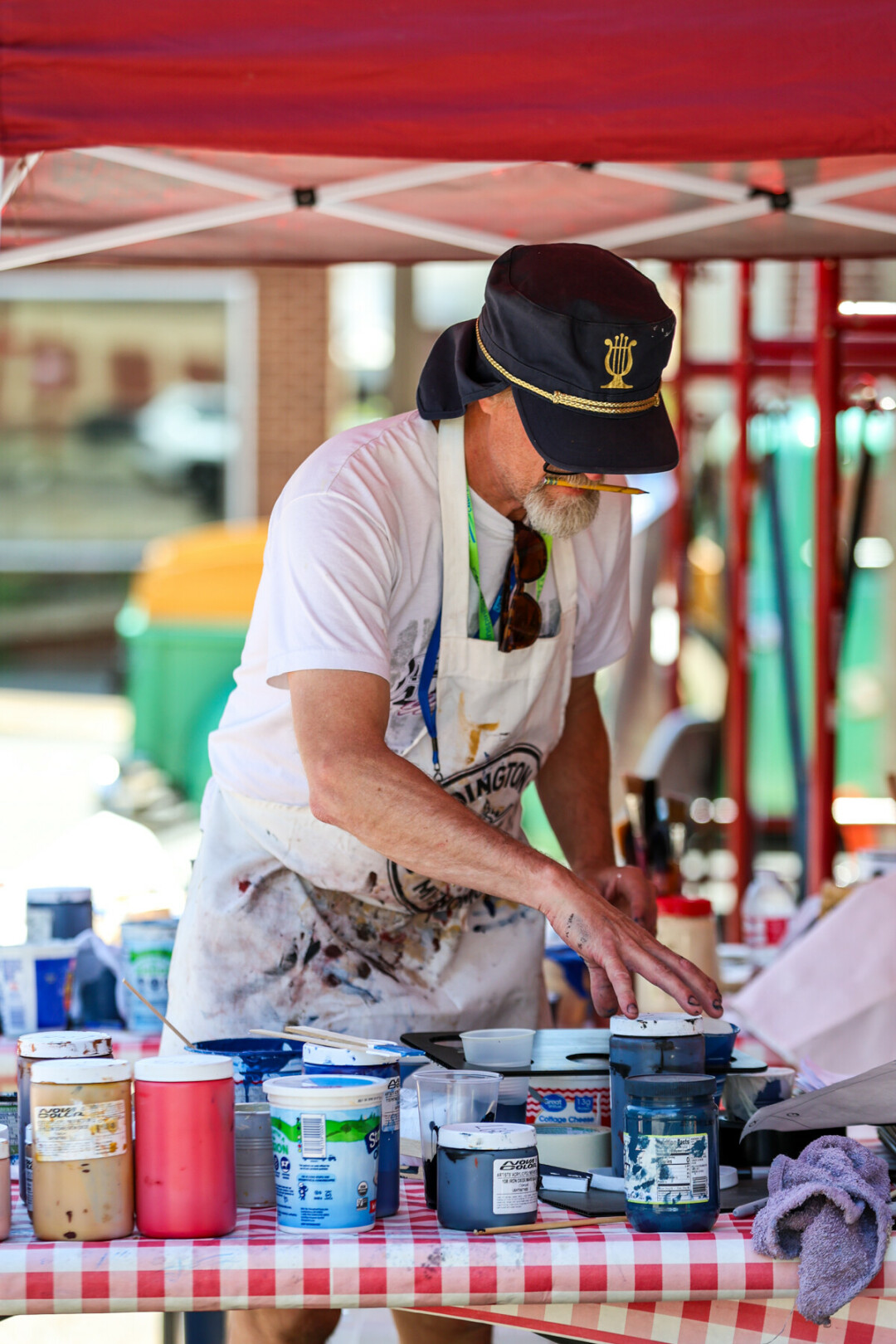Man with a hat looking at paint canisters on table