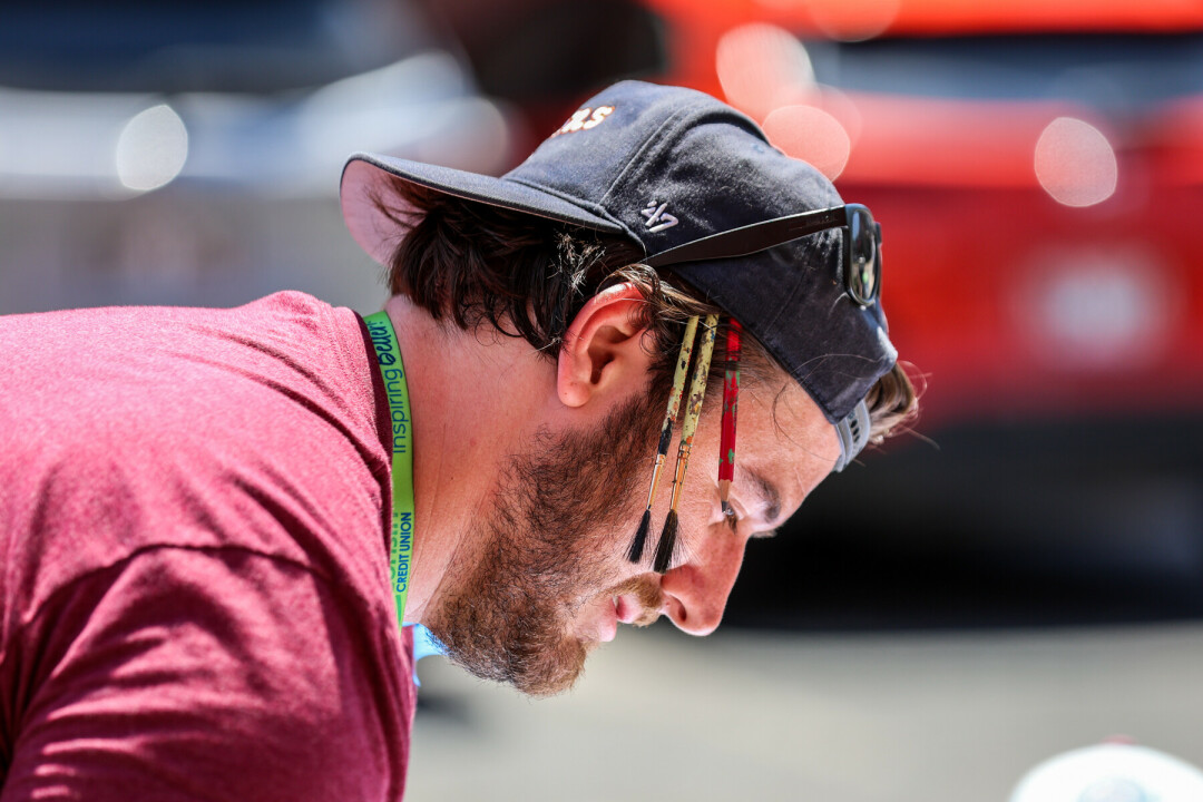 Man with hat and sunglasses on his head with paintbrushes stuck in the side of the hat