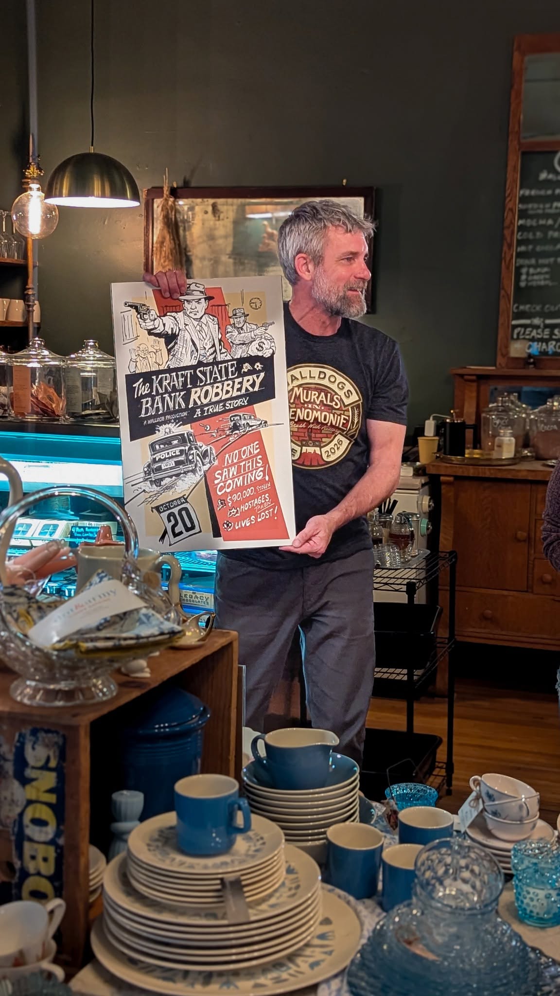 Man holding painted sign replica of large mural
