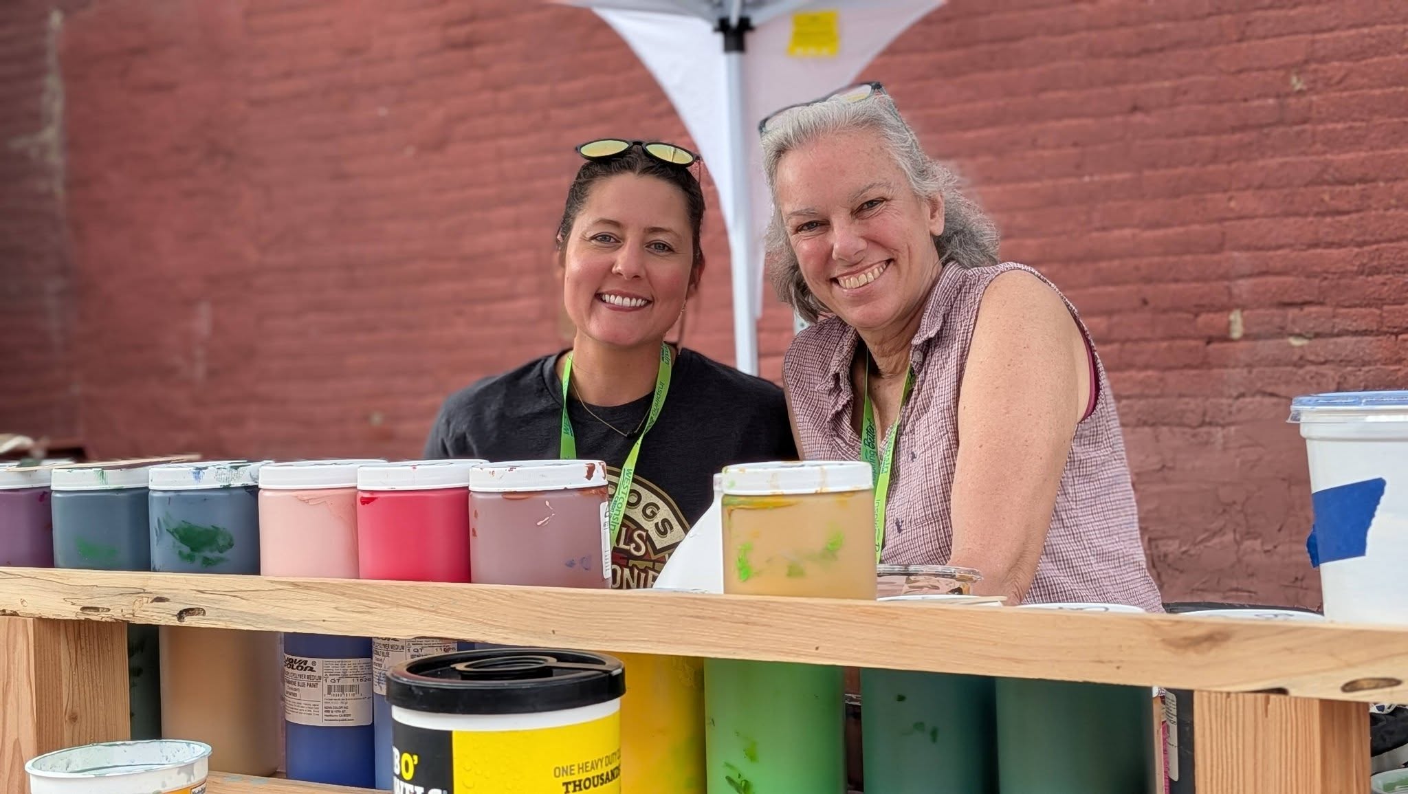 Ladies behind paint canisters smiling