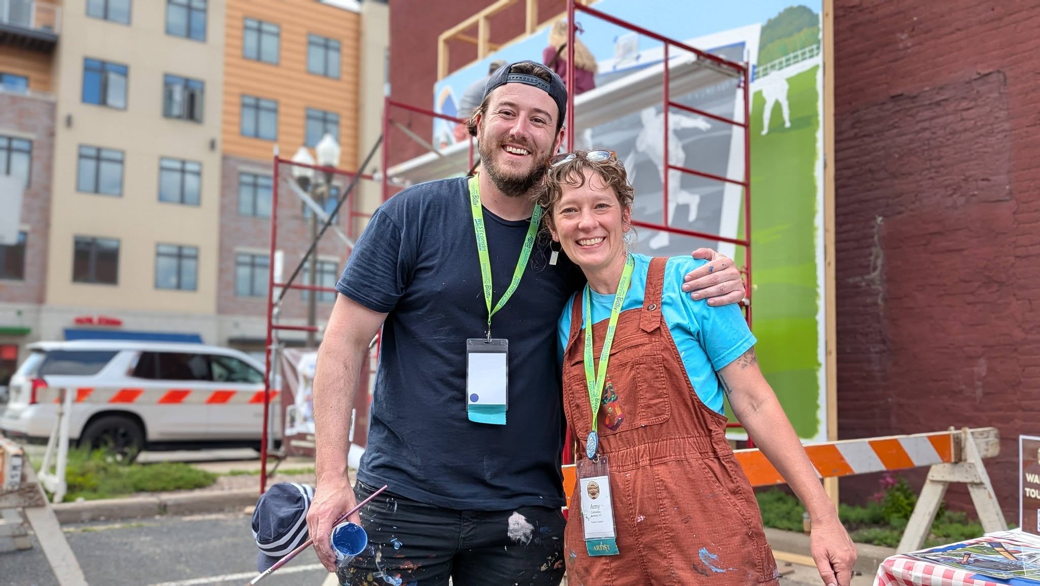 Two artists in paint covered clothes smiling
