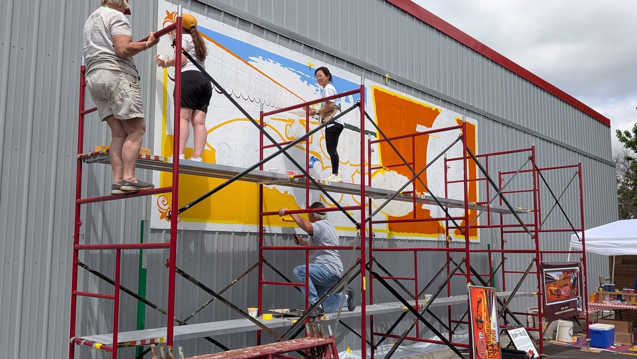 Artists on scaffolding climbing and painting