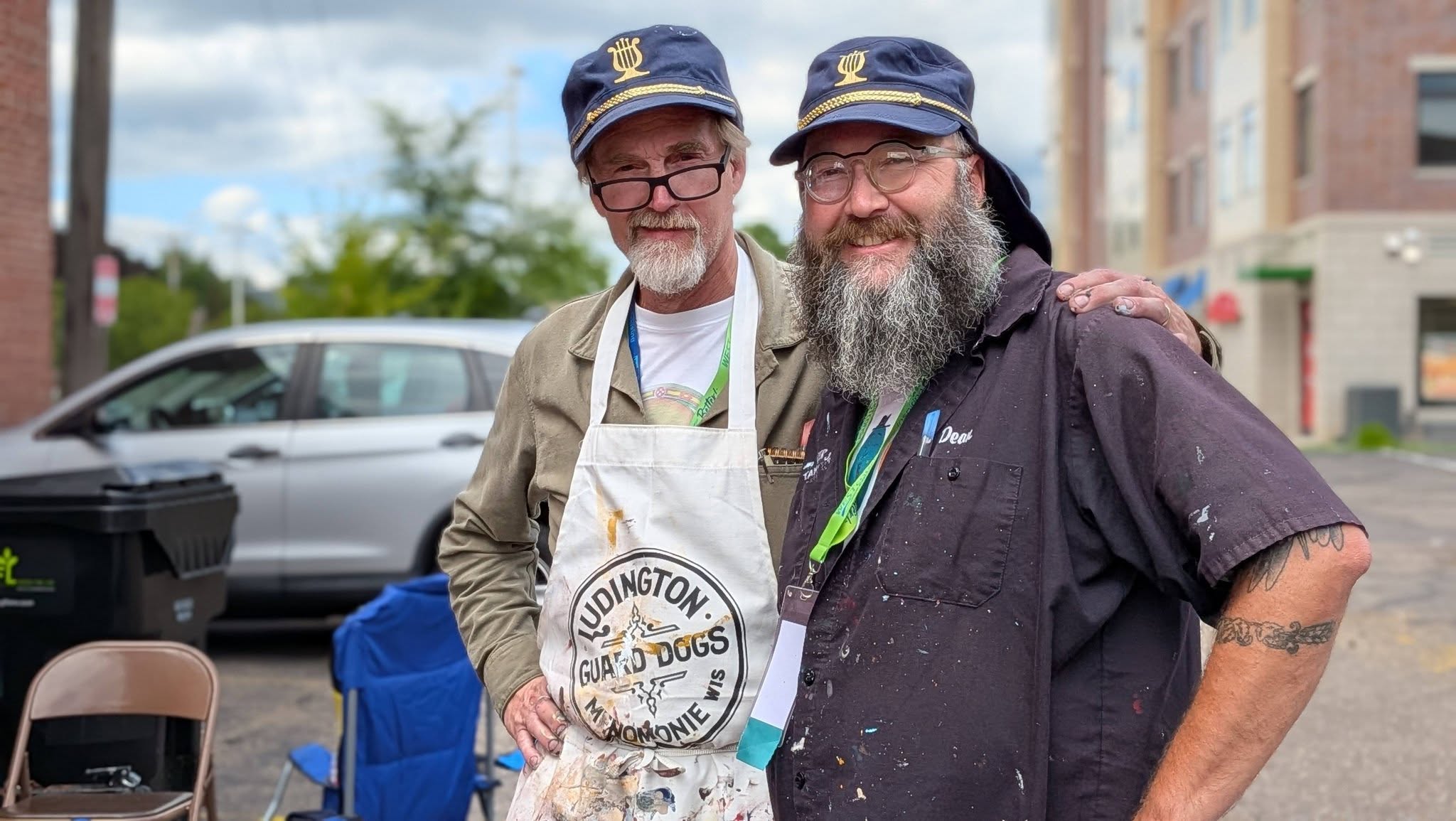 Two artists with blue hats together with paint covered clothing