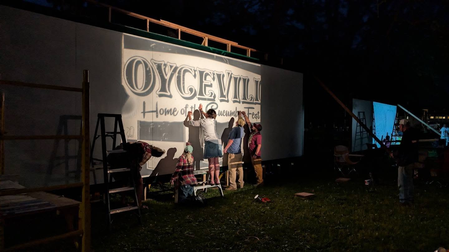 Artists sketching at night while the image is projected onto the area