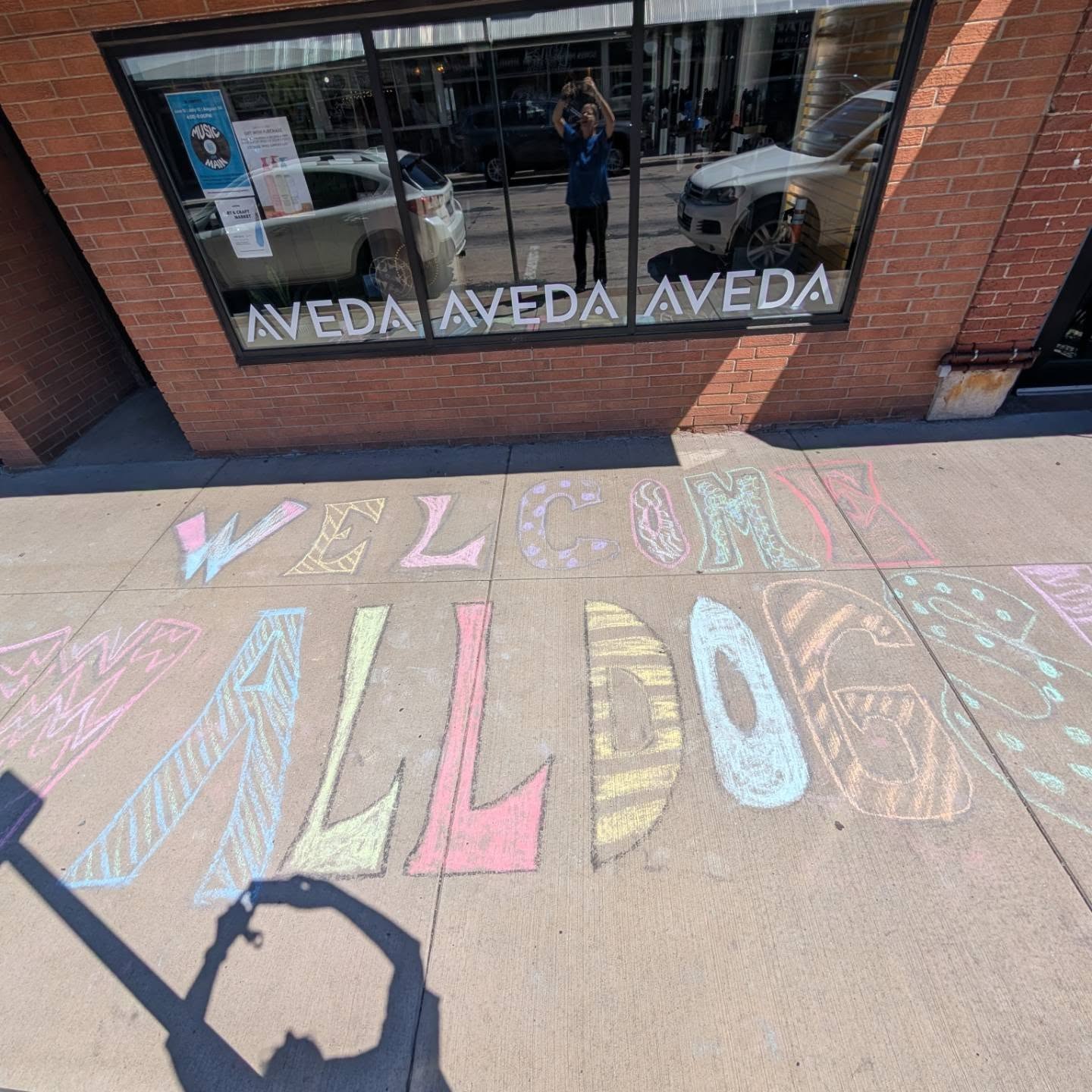 Aveda salon with welcome walldogs written in chalk outside on the sidewalk