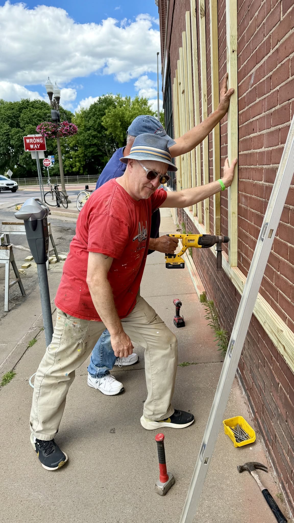 Guys leaning a 2x4 against the wall and securing with a drill
