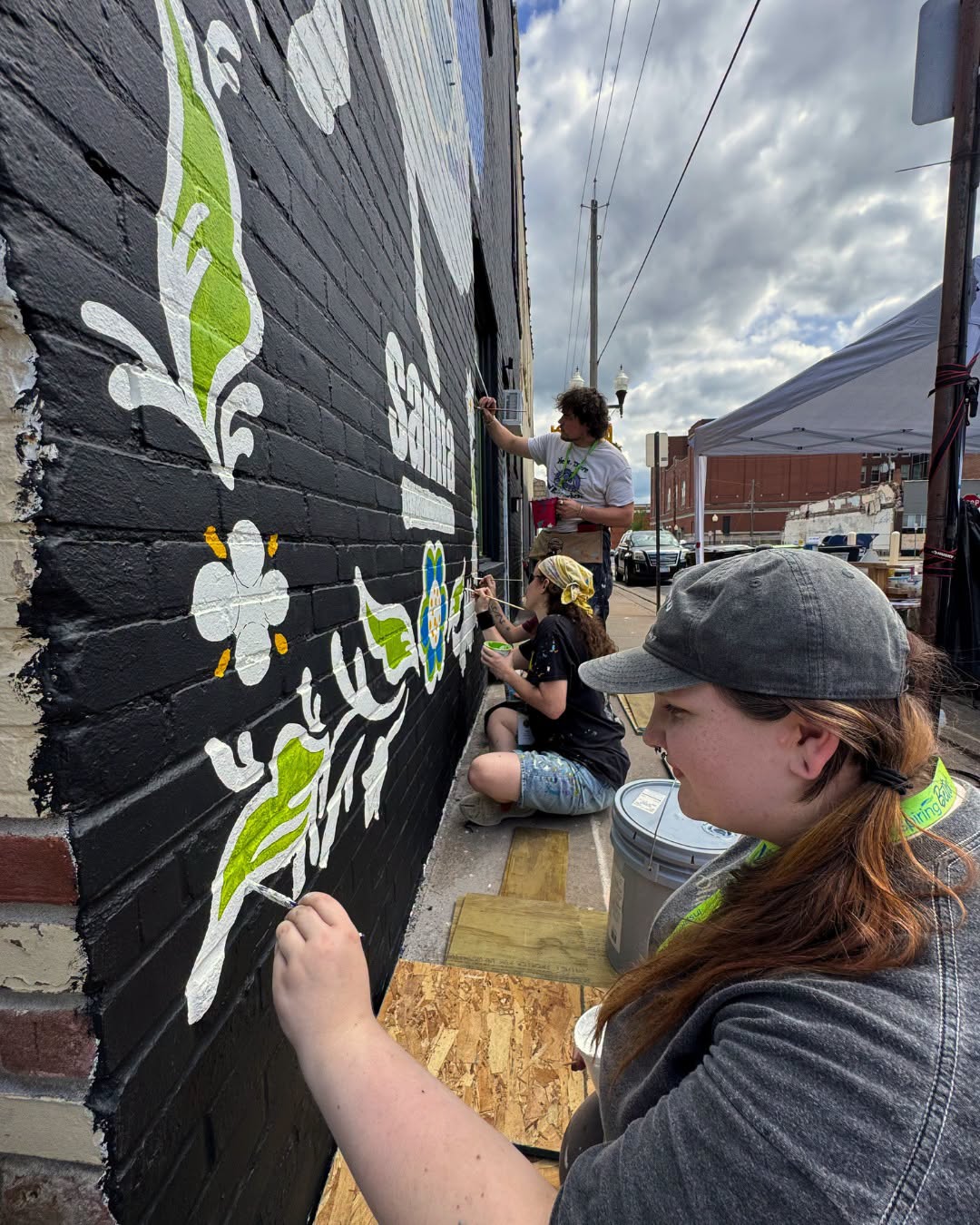 Close up of people painting on a black brick wall
