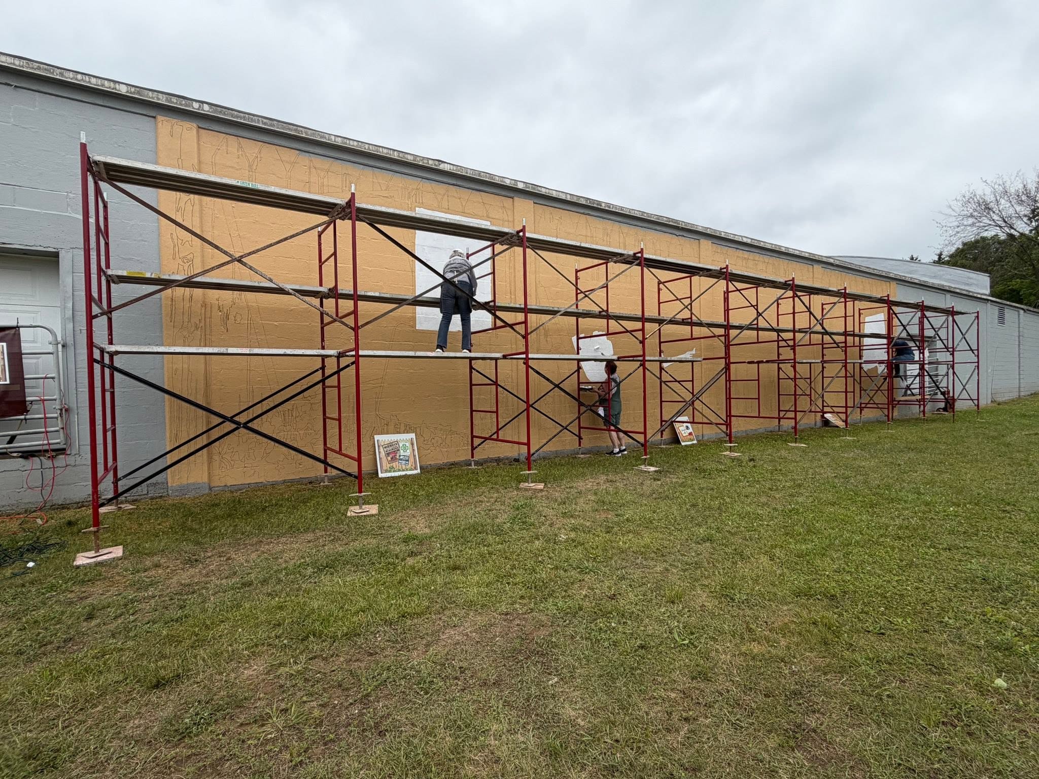 Scaffolding all across a long wall that is beginning to get painted