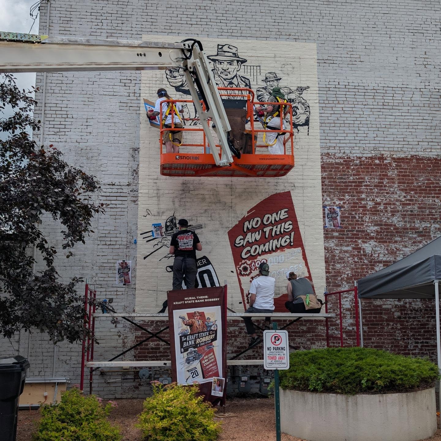 Artists on a mural and below that on scaffolding painting various areas
