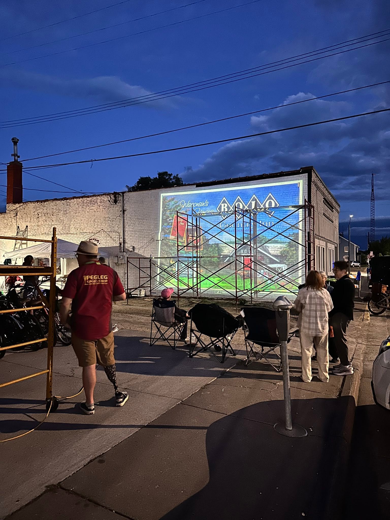People watching as a design is projected onto a wall during an evening