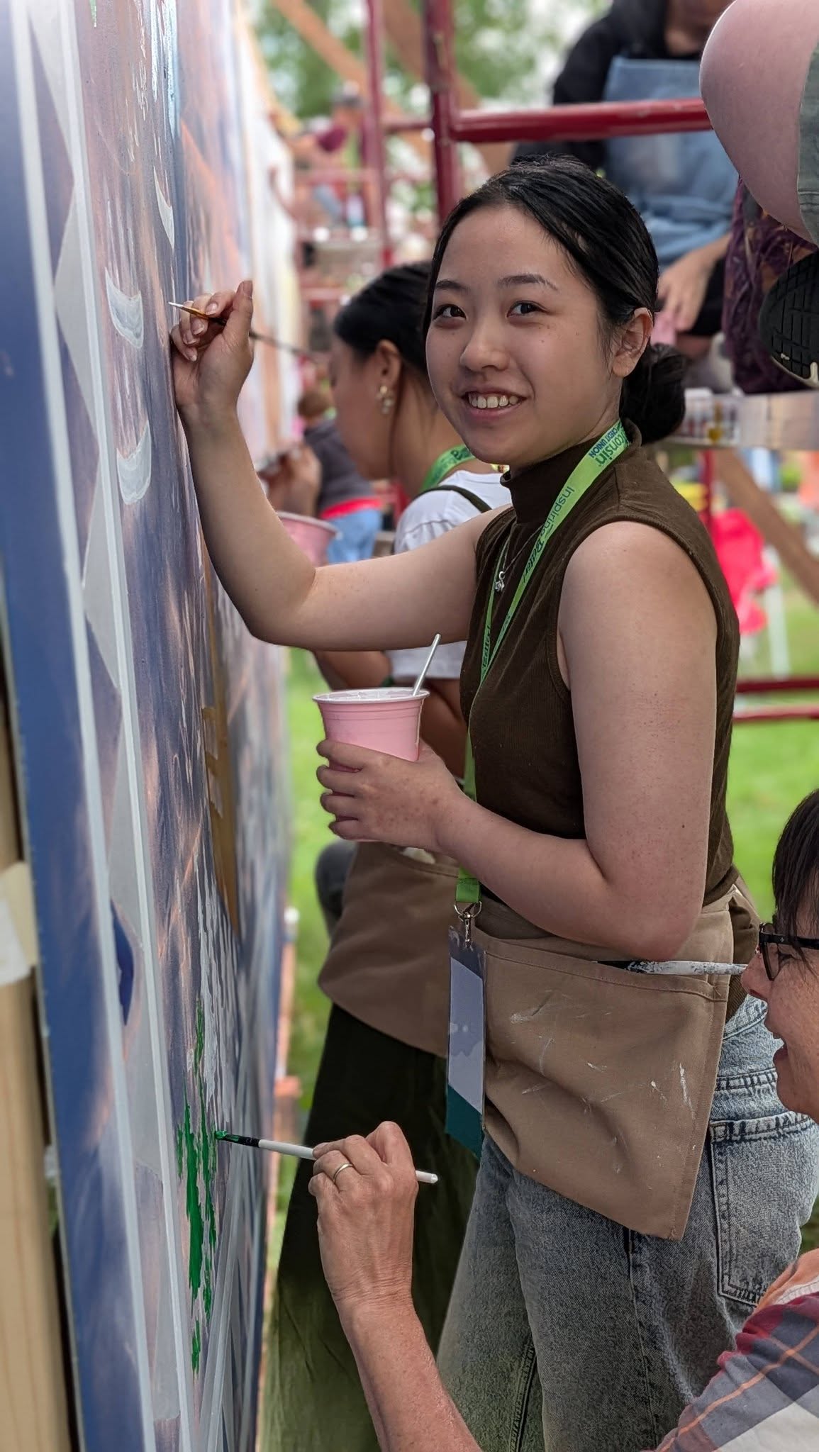Woman holding a cup of paint and painting on a wall
