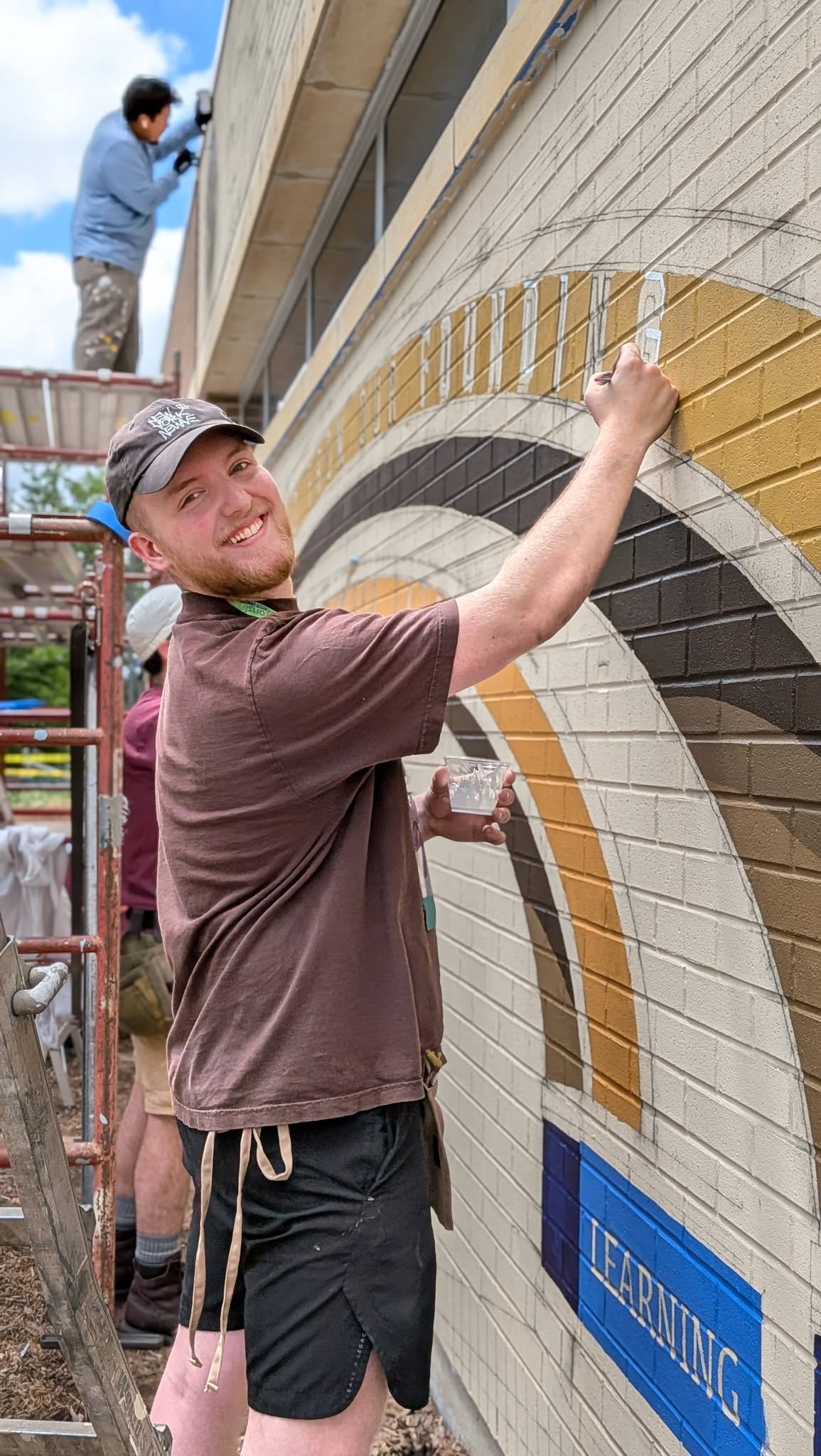 Artist painting a mural and smiling at the camera