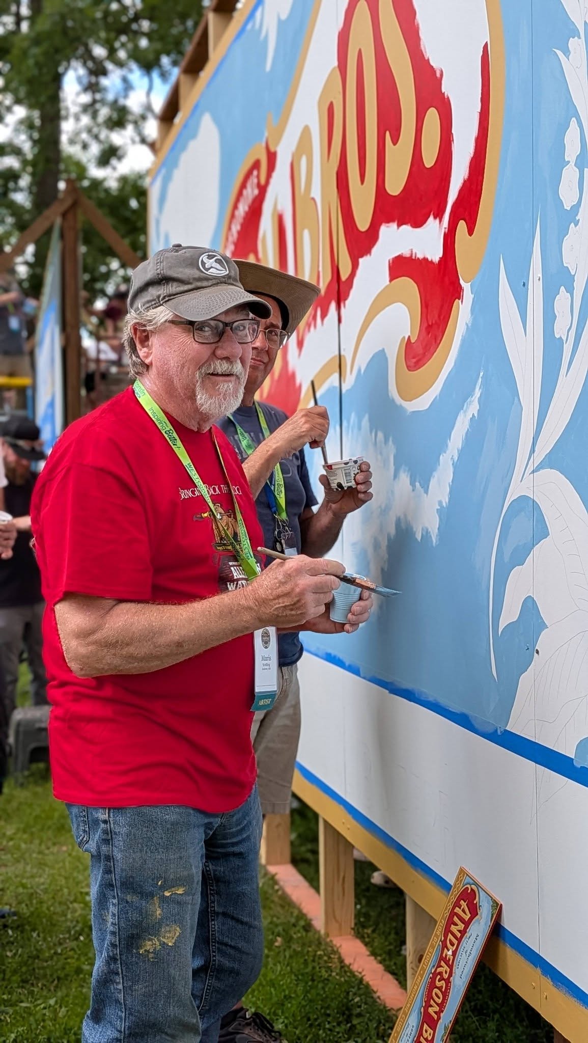 two artists with paint brushes standing in front of a mural