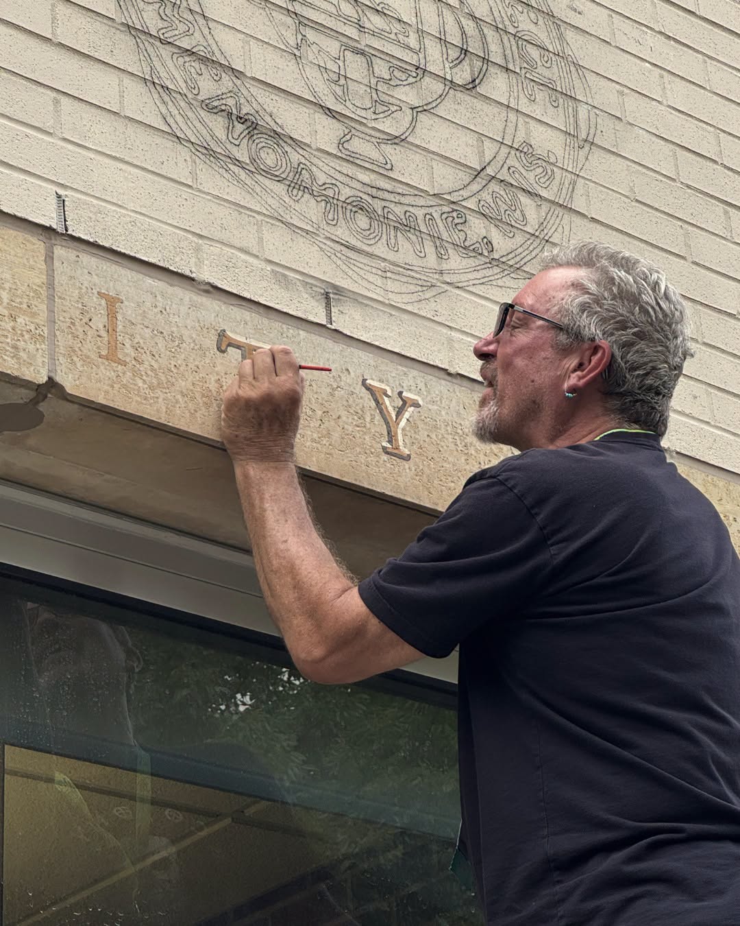 Artist painting details on letters in a mural