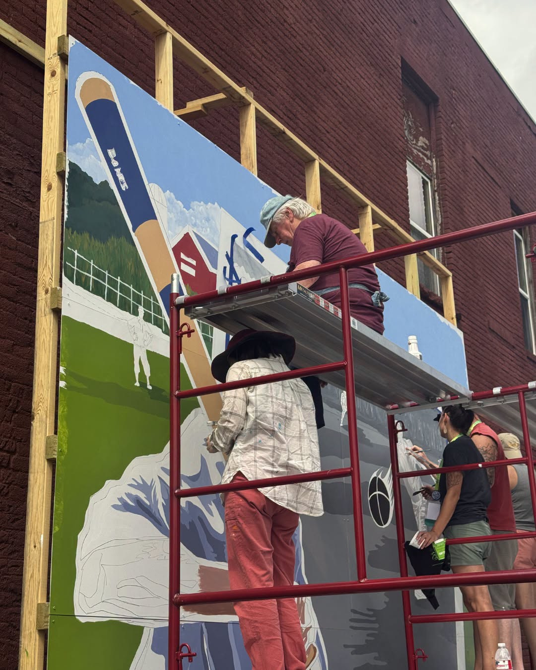 People on different levels of scaffolding painting a mural