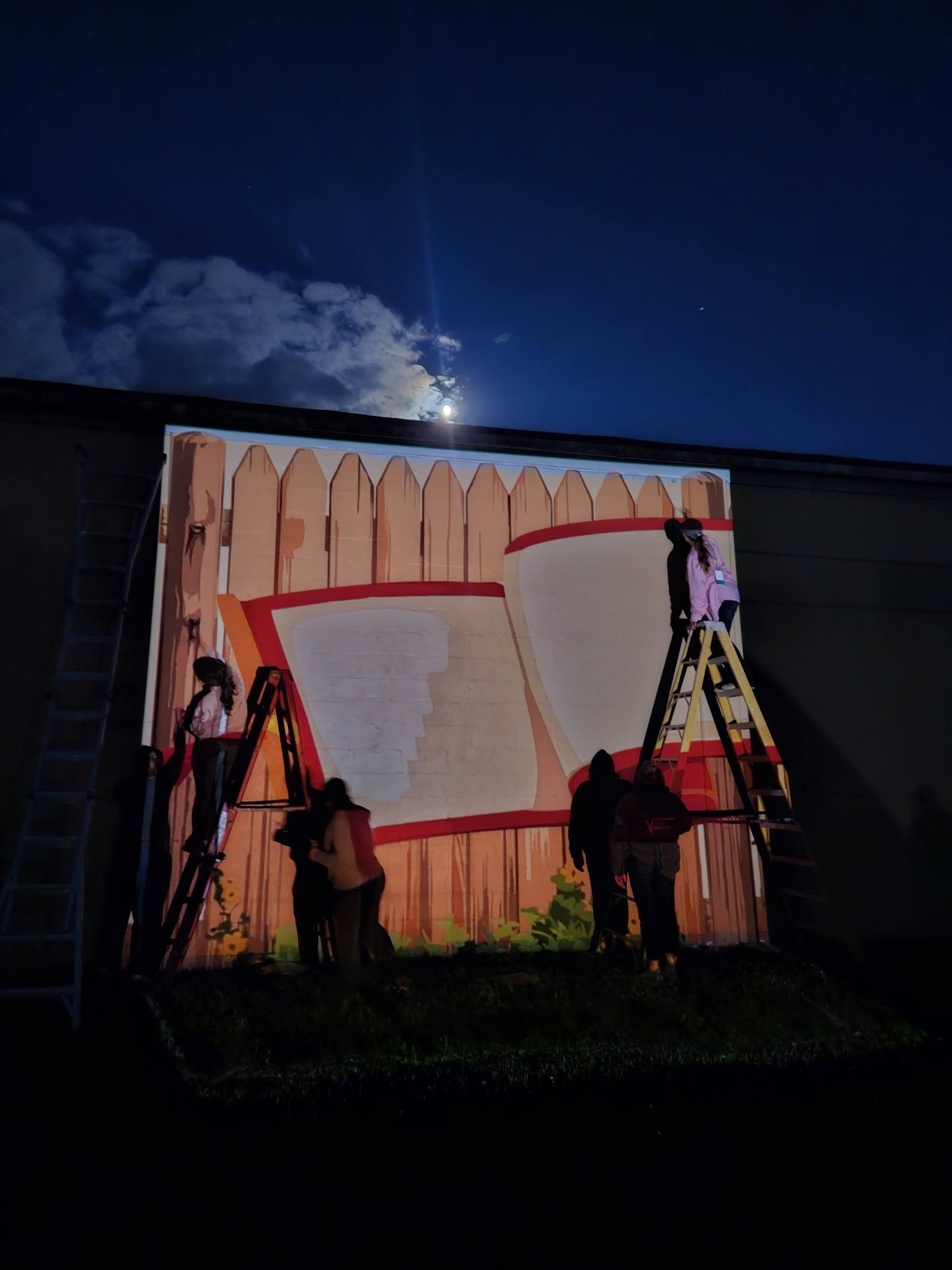 Artists painting in the dark with artwork projected on to the wall