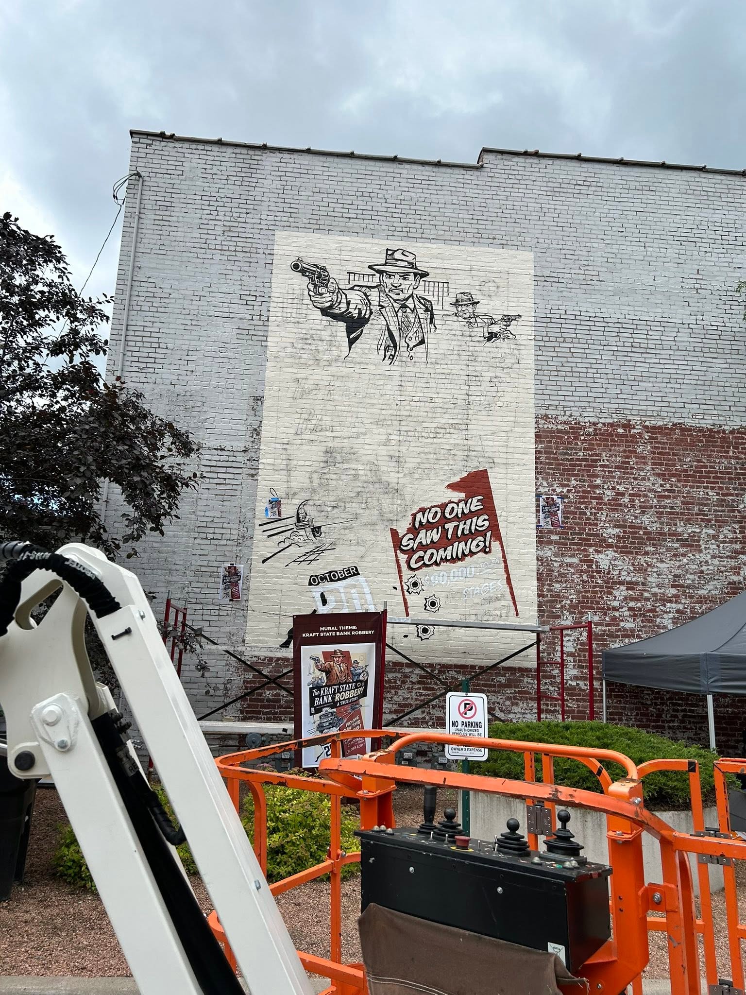 Beginning to paint a mural on a brick wall with a view from the lift