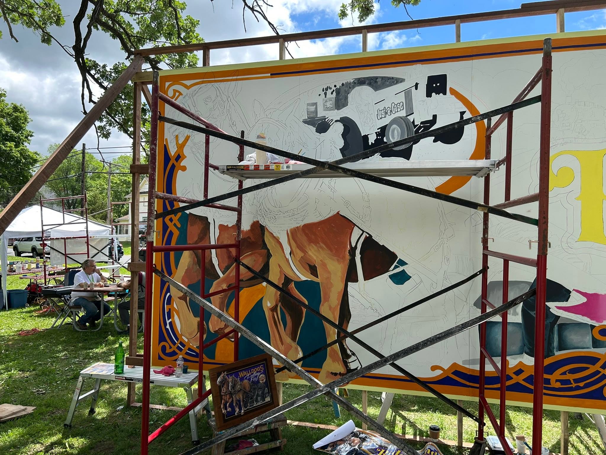 beginning to paint the mural of horses with scaffolding in front of mural