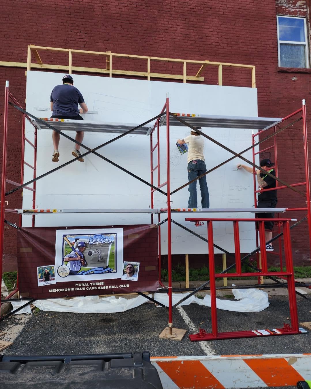 Artists starting to sketch out image on an empty mural space