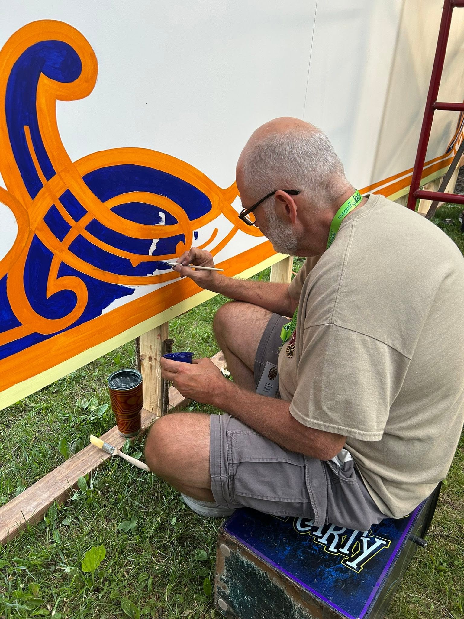 Man seated in front of a mural painting