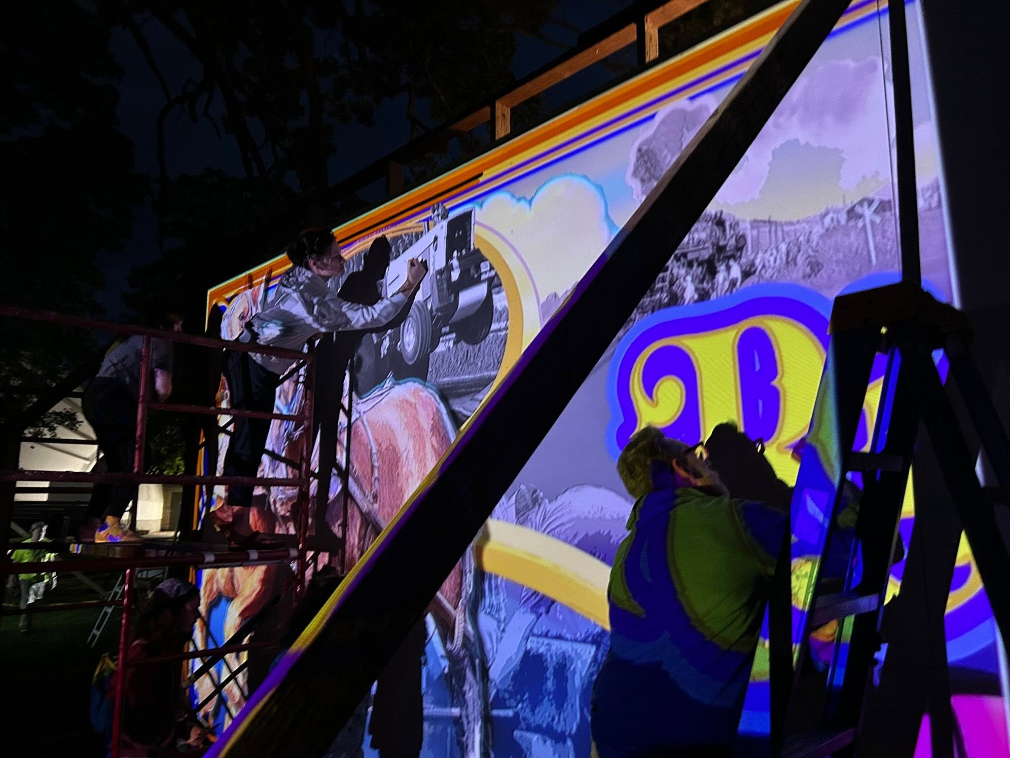 Artists stenciling and painting in the dark with image projected