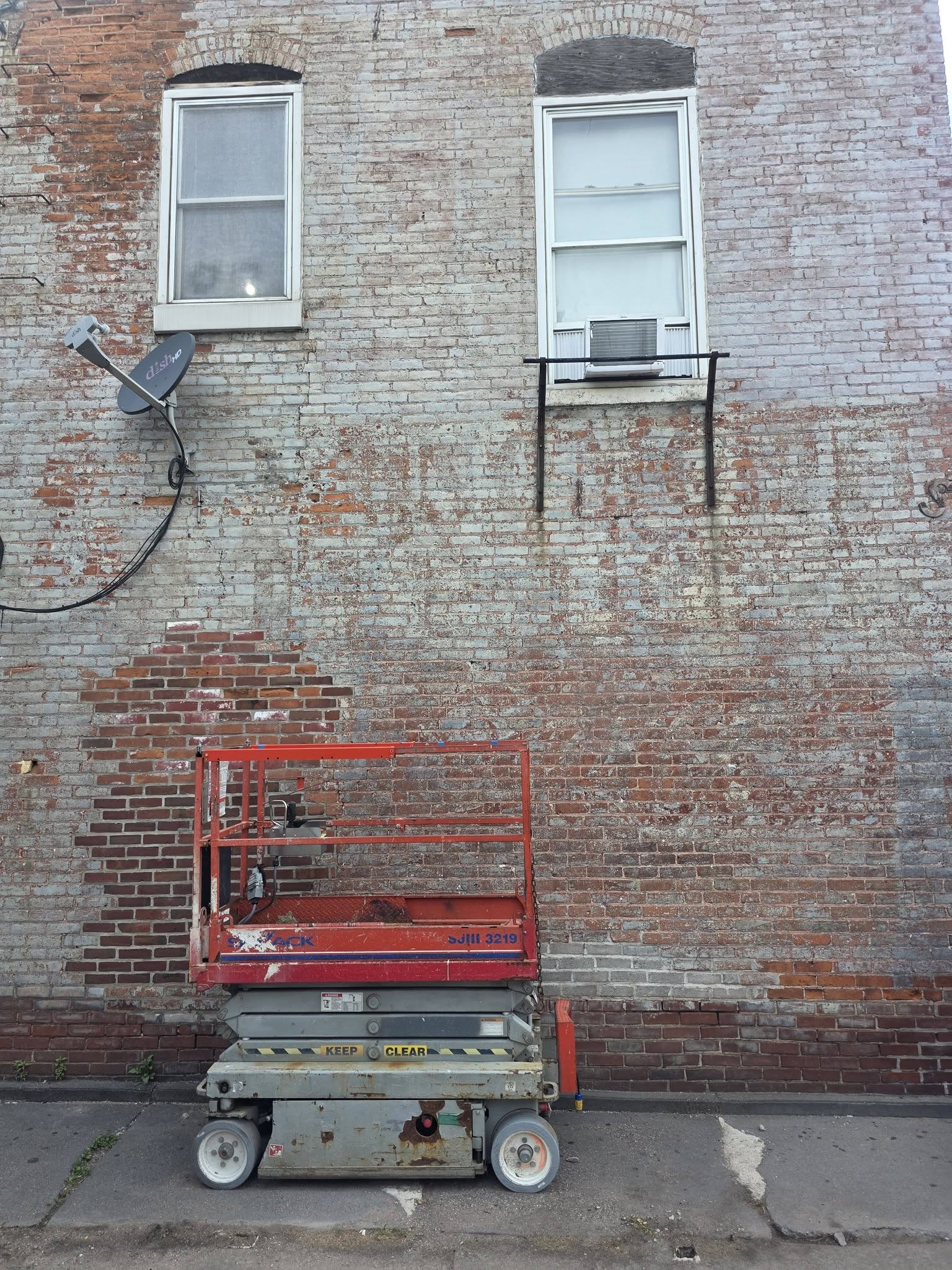 Scissor lift seated in front of an old brick wall