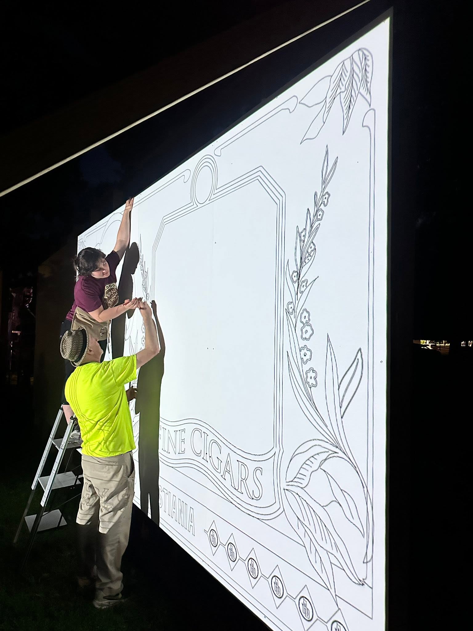 Artists stenciling out design for a mural