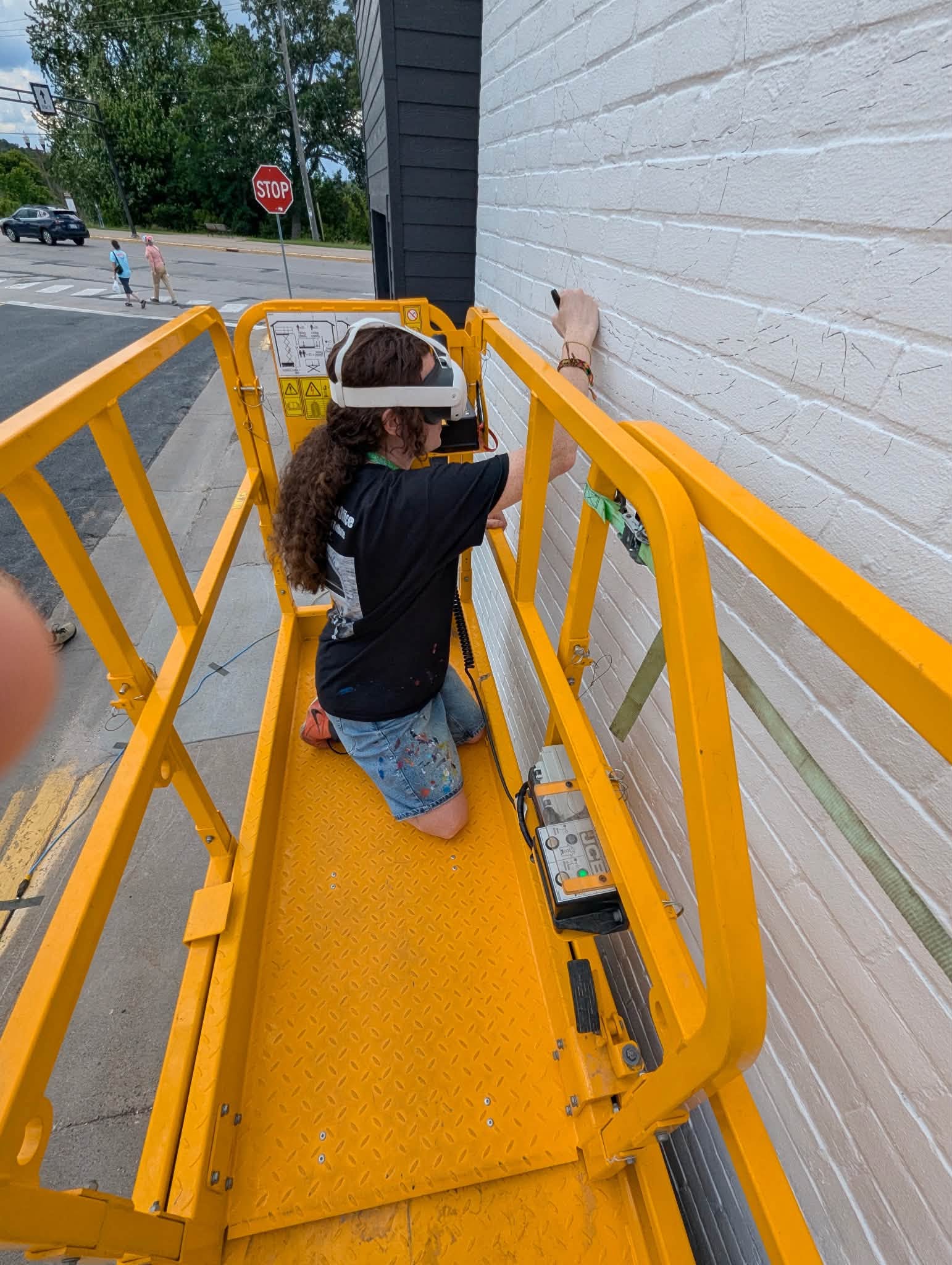 girl with meta goggles drawing on a wall inside scissor lift