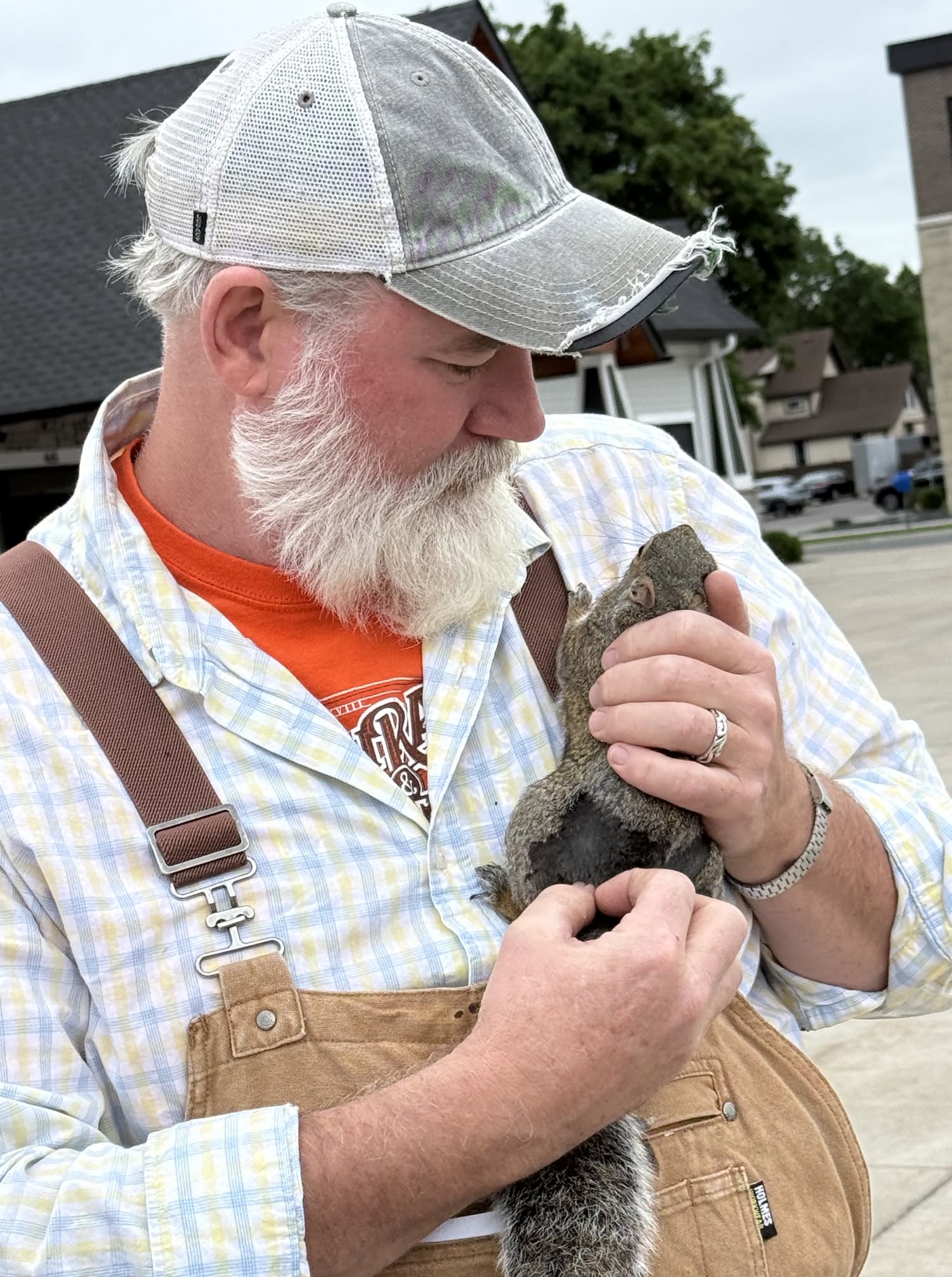 Man in a ball cap holding a squirrel