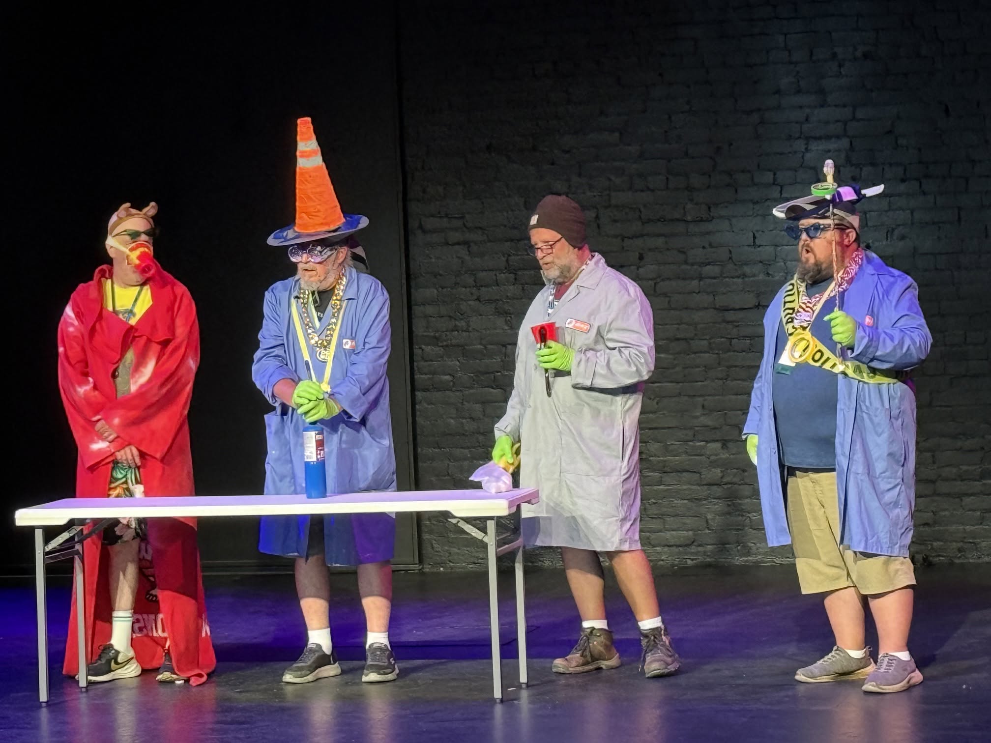 Four people in large coats and costumes on a stage