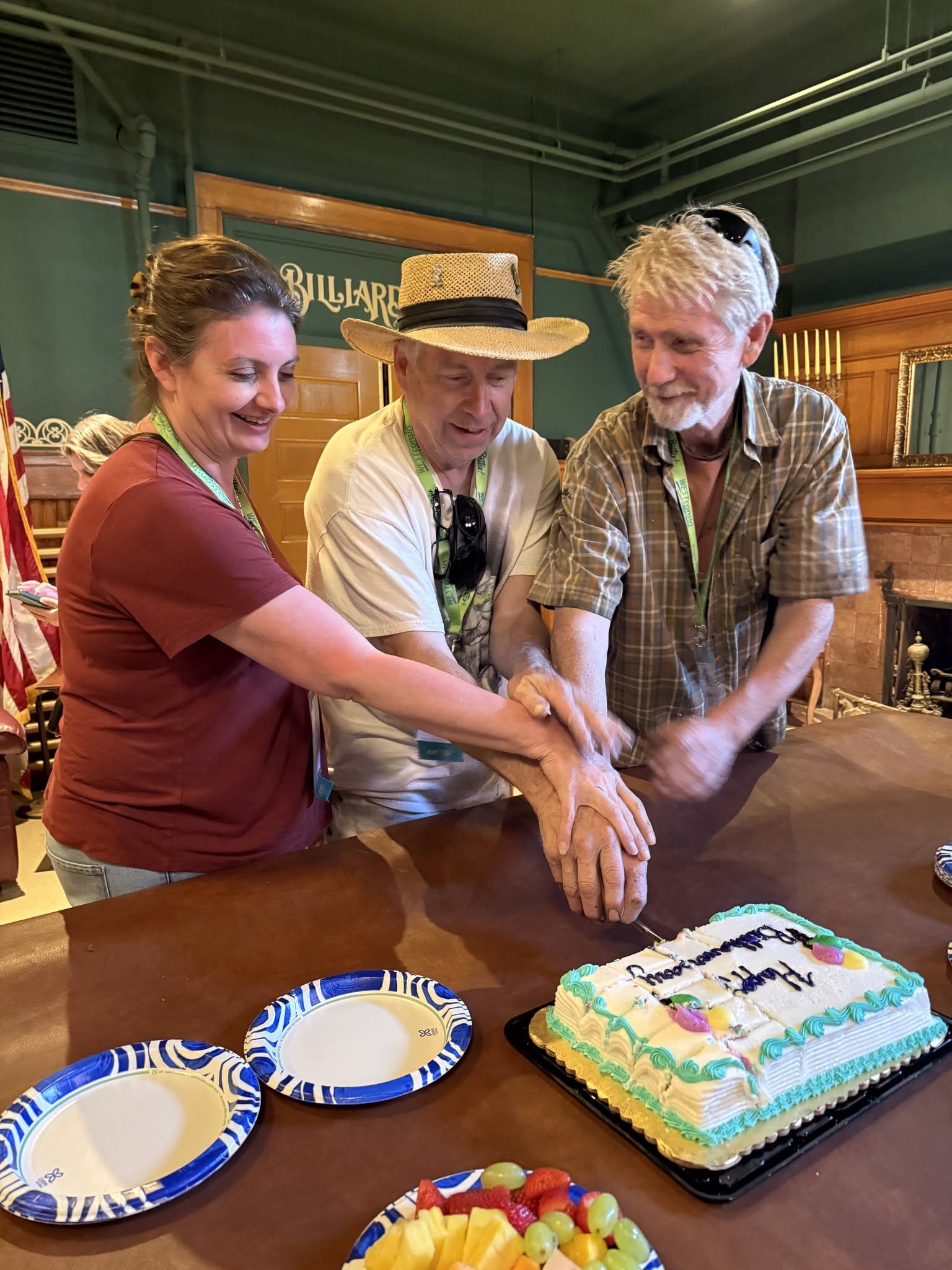 Three people cutting into a cake together