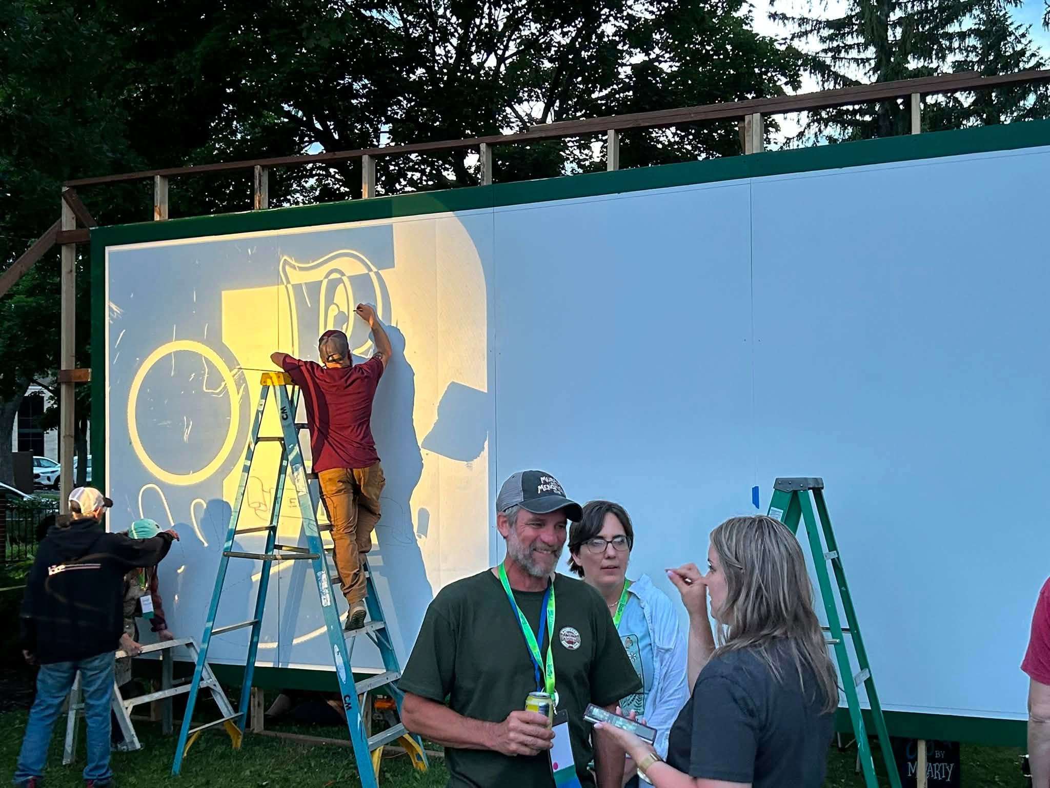 Artists Drawing on large billboard with people talking in front