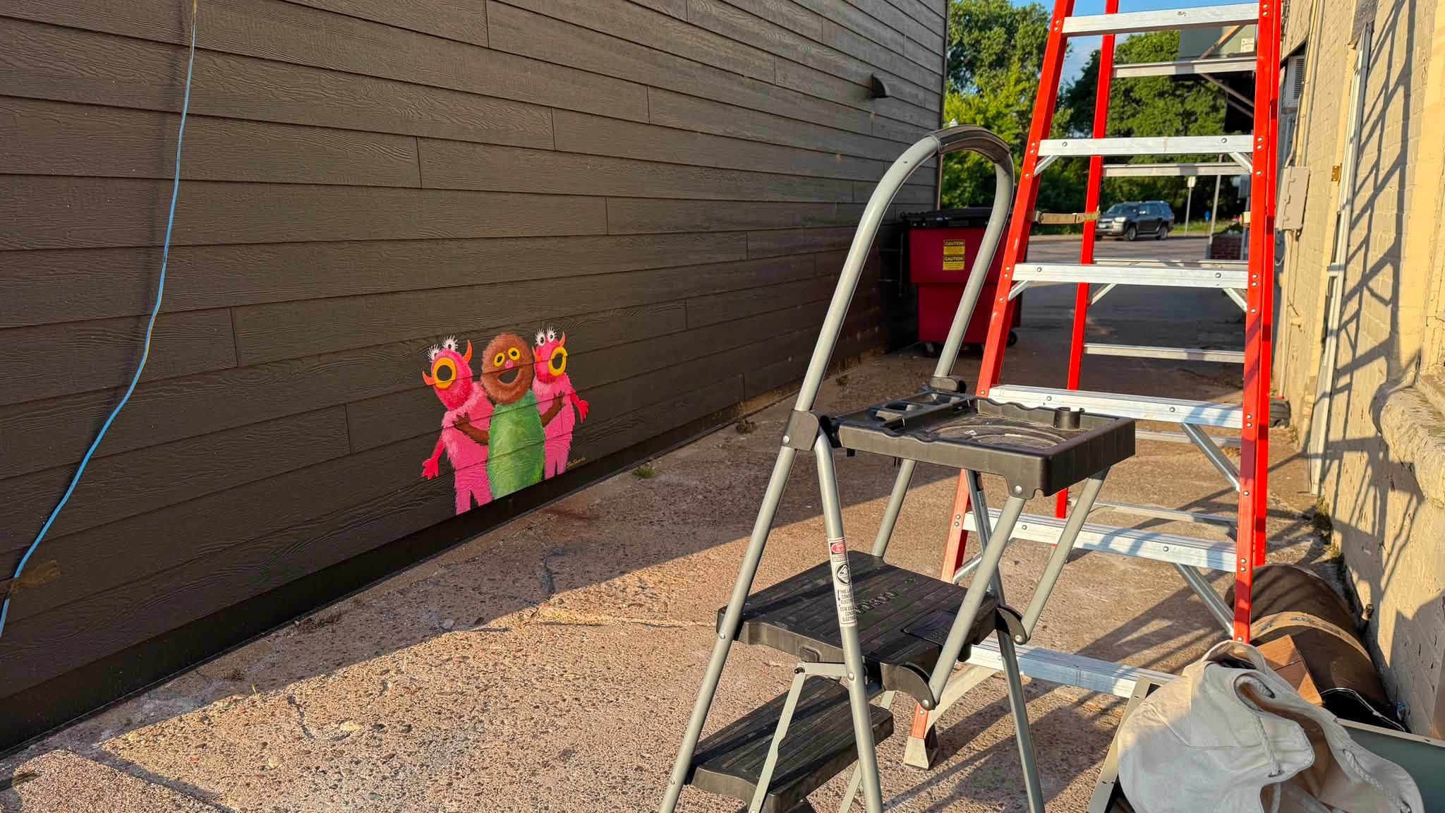 Ladders next to a wall painted with little monsters