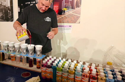 Man pouring paint into containers with multiple bottles of paint