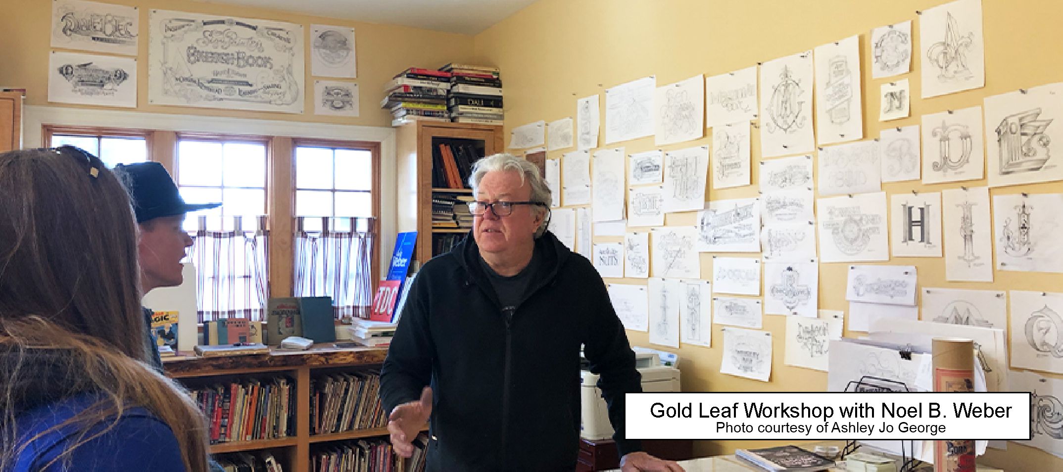 Noel Weber in front of a wall of sketches